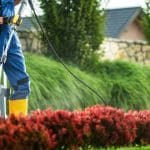 A man in overalls operates a pressure washer to remove dirt