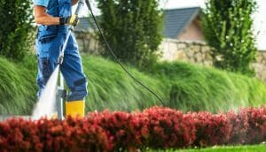 A man in overalls operates a pressure washer to remove dirt