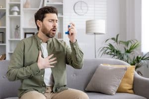 Man experiencing breathing difficulty while using asthma inhaler