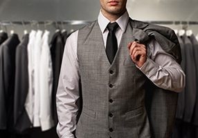 Businessman in classic vest against row of suits in shop