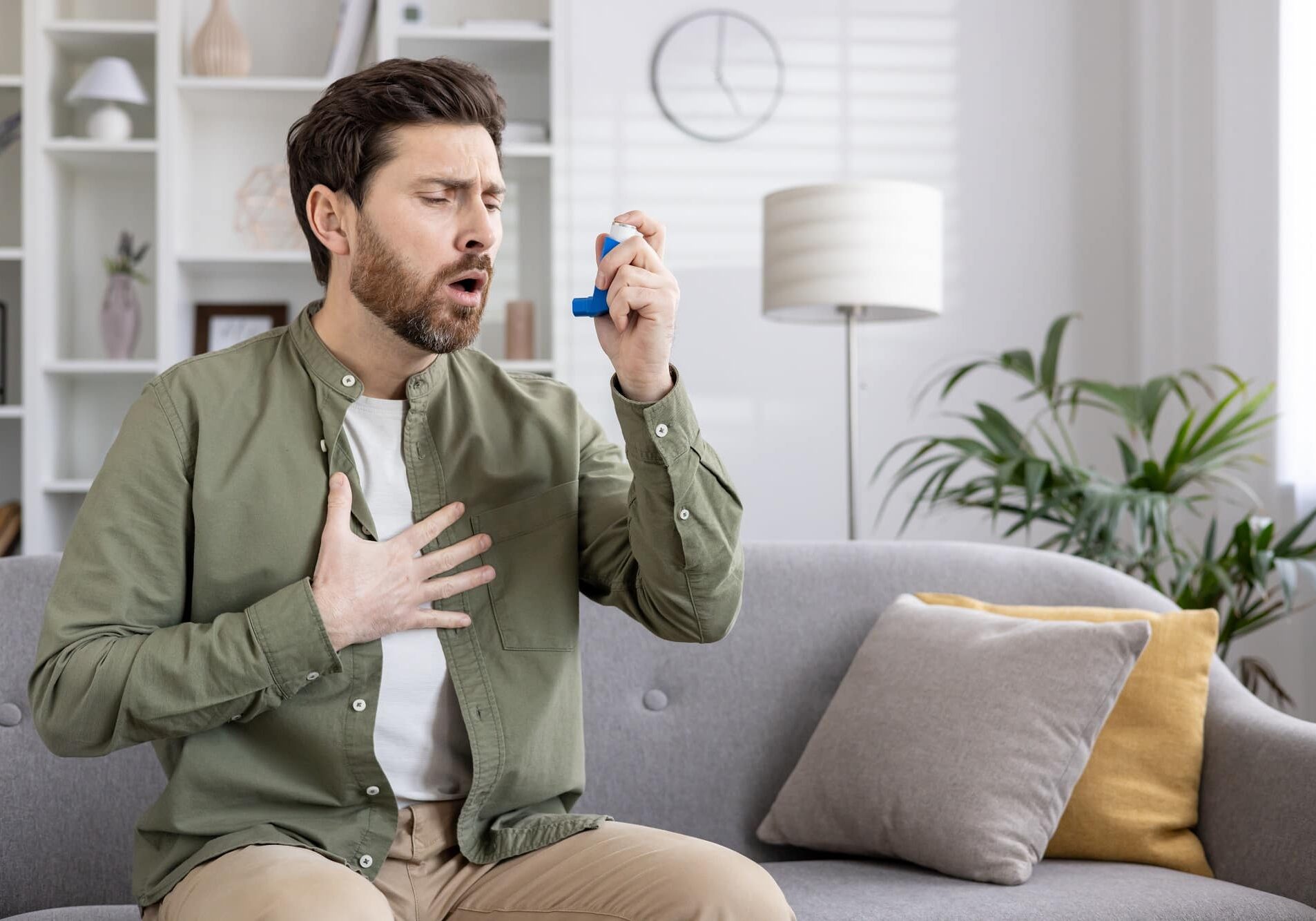 Man experiencing breathing difficulty while using asthma inhaler