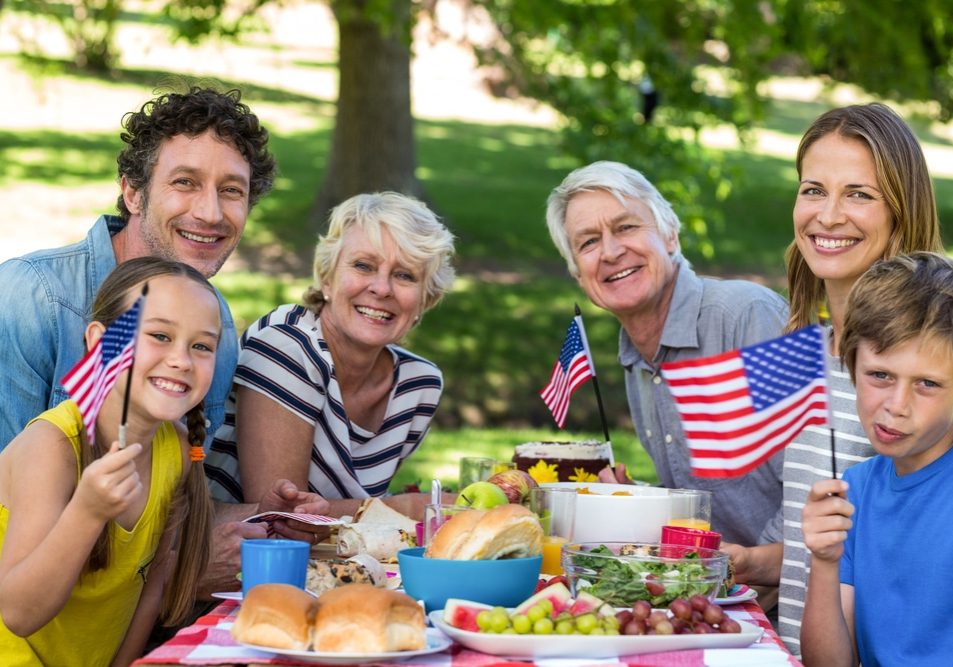Family with American flag having a picnic in a park