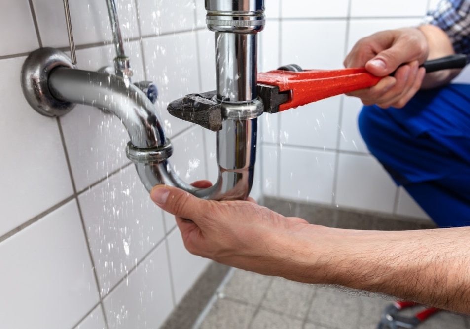 Male Plumber's Hand Repairing Sink Pipe Leakage With Adjustable Wrench