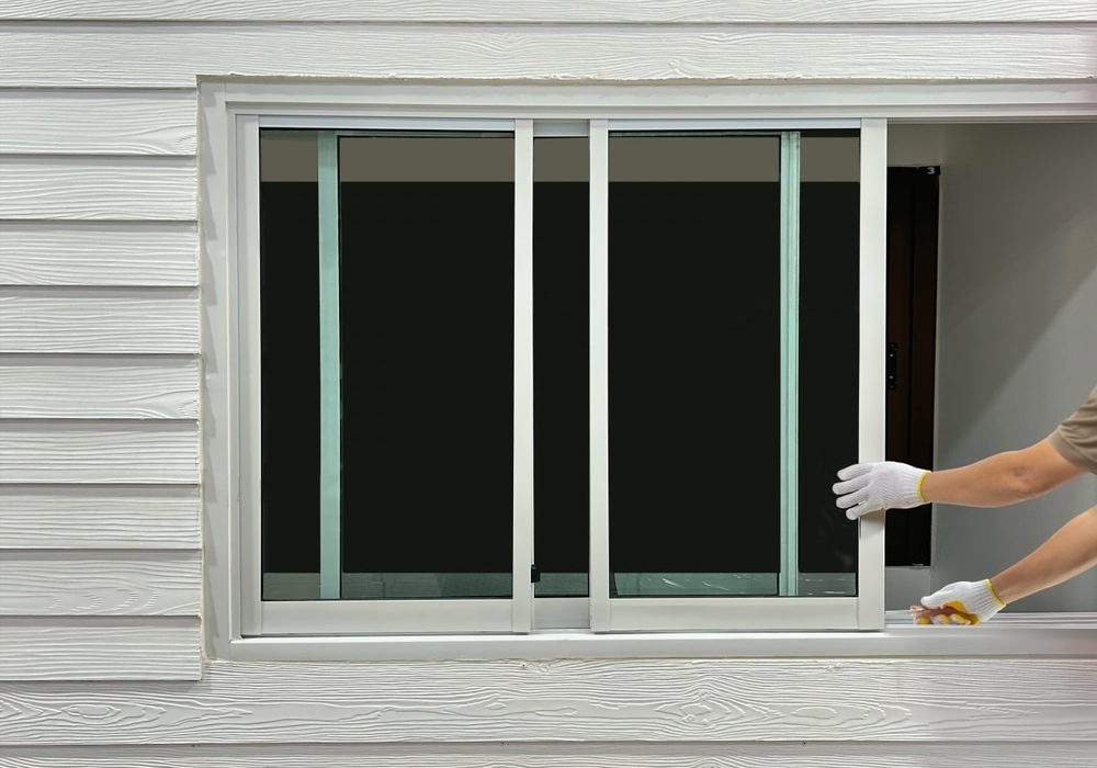 Construction,Worker,Repairing,The,Sliding,Window,On,Artificial,Woods,Siding. Construction worker repairing the sliding window on artificial woods siding.