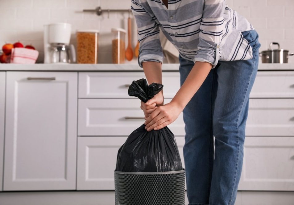 Woman taking garbage bag out of bin at home Woman taking garbage bag out of bin at home