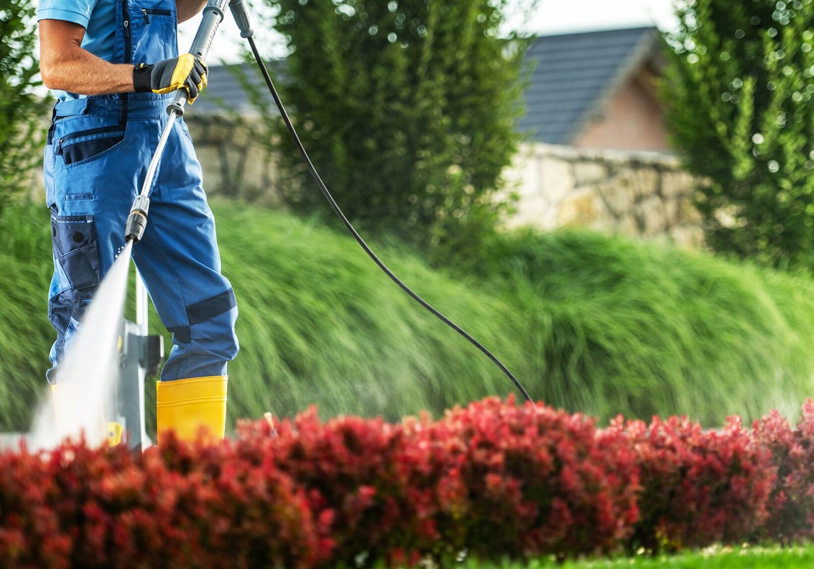 A man in overalls operates a pressure washer to remove dirt