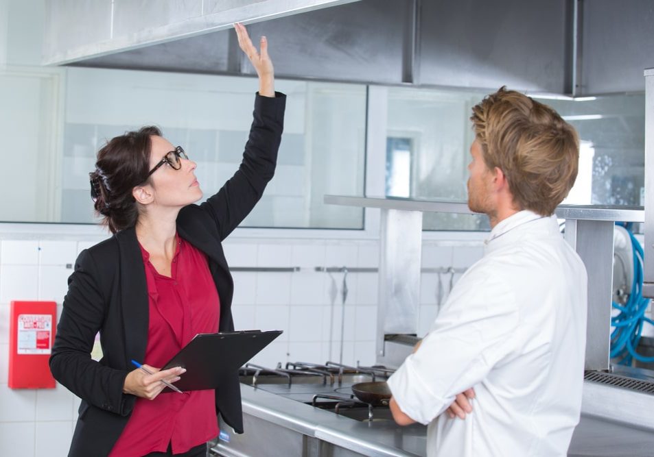 Woman,Undergoing,Inspection,In,Restaurant,Kitchen,With,Chef woman undergoing inspection in restaurant kitchen