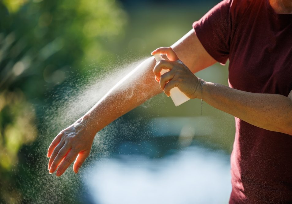 Woman Applying Insect Repellent On Her Arm Outdoors Woman Applying Insect Repellent On Her Arm Outdoors